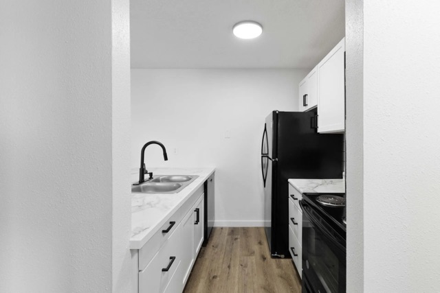 Renovated galley kitchen with black appliances at The Cypress